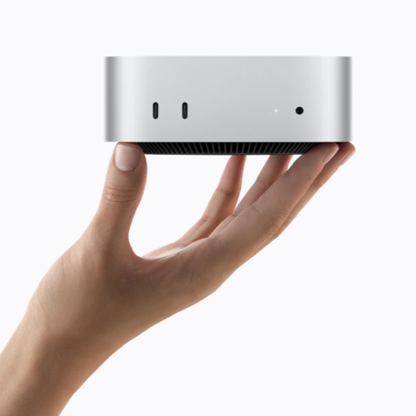 手持银色 Mac mini，展示正面接口